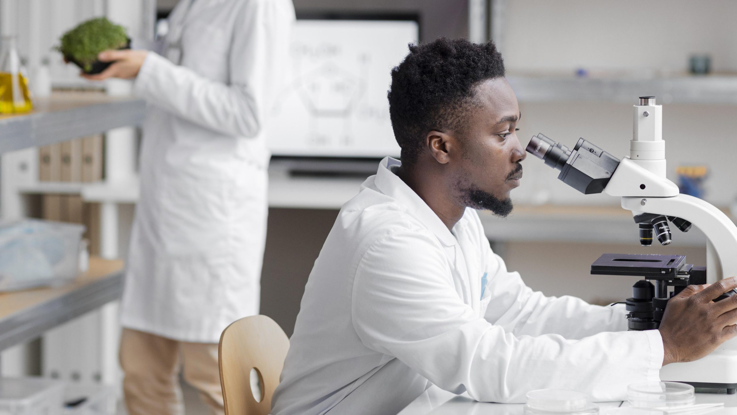 Fotografia de cientista negro olhando microscópio em laboratório