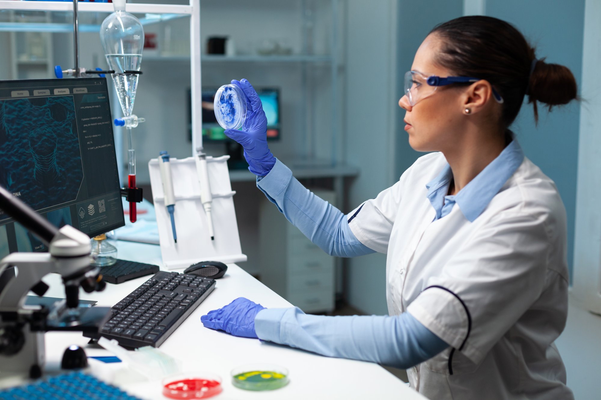 biologist-researcher-woman-holding-transparent-petri-dish-analyzing-blue-solution