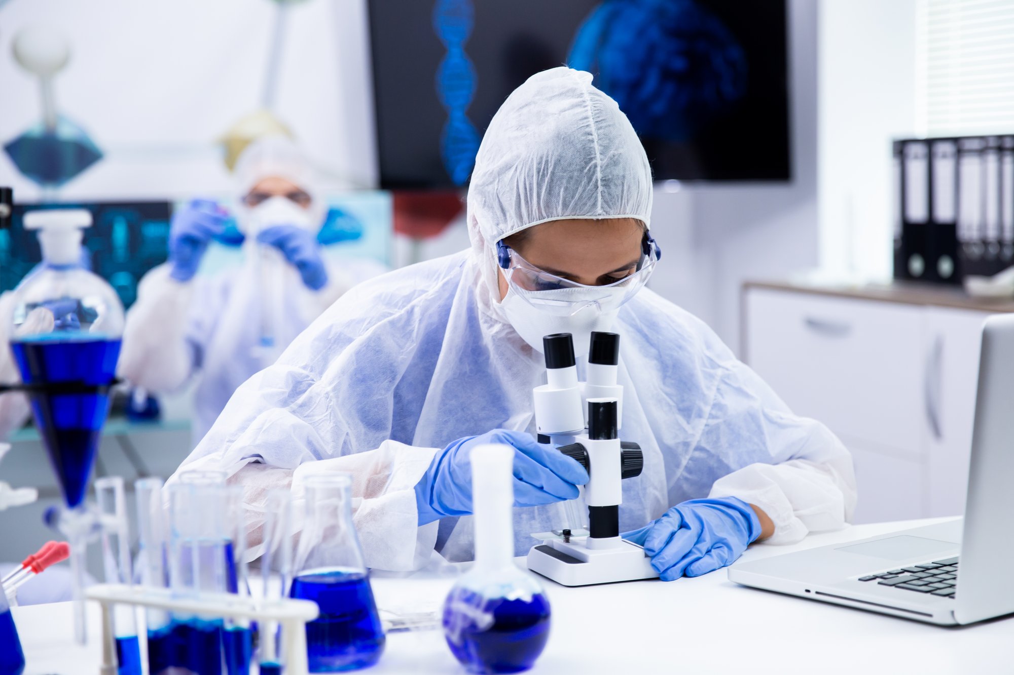 female-scientist-looking-through-microscope-research-laboratory-smoking-blue-liquid-test-tubes