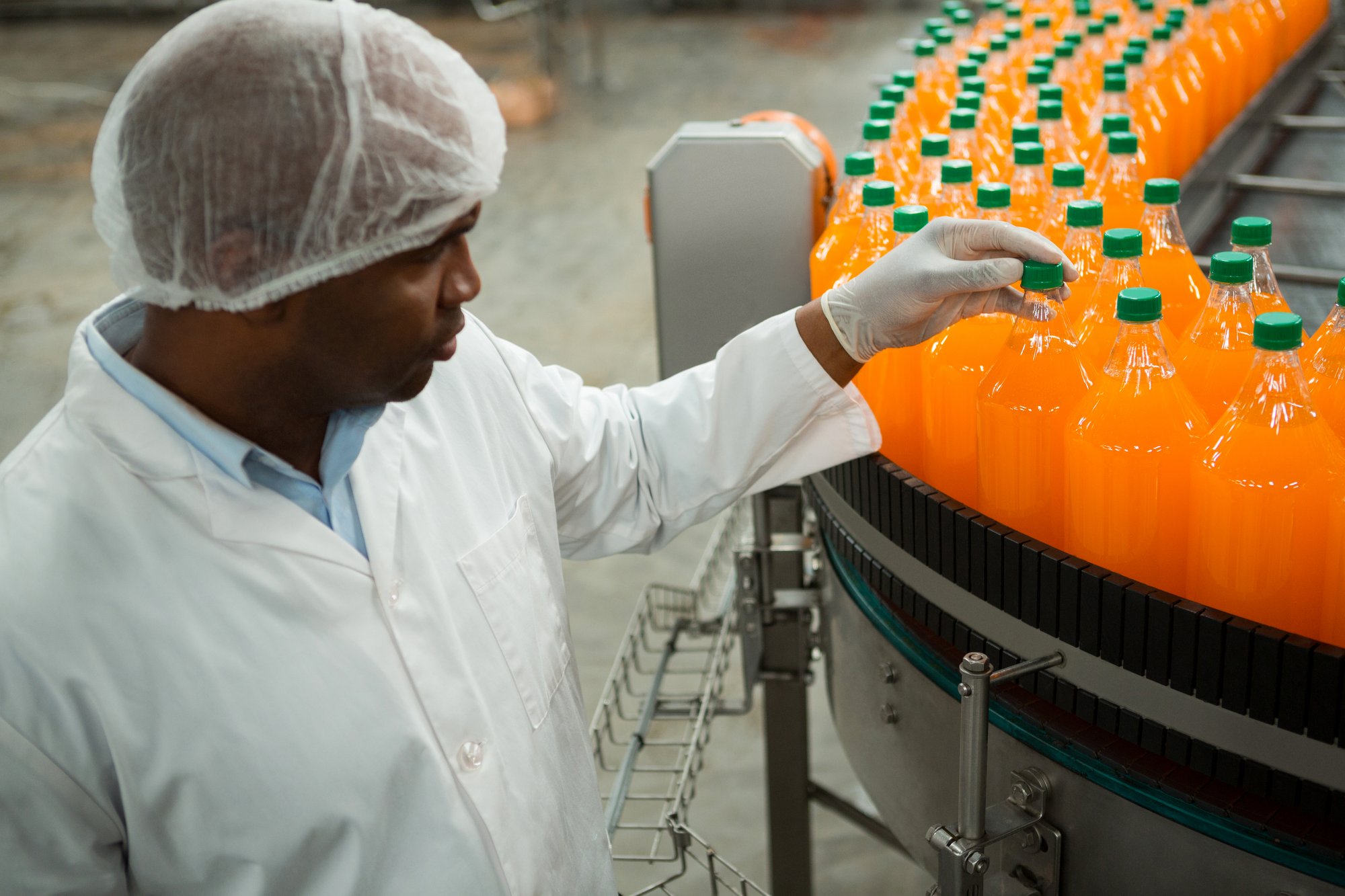 serious-male-worker-examining-bottles-juice-factory