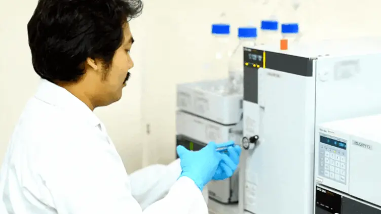 Analista operando cromatógrafo líquido de bancada, integração da cromatografia com o LIMS.